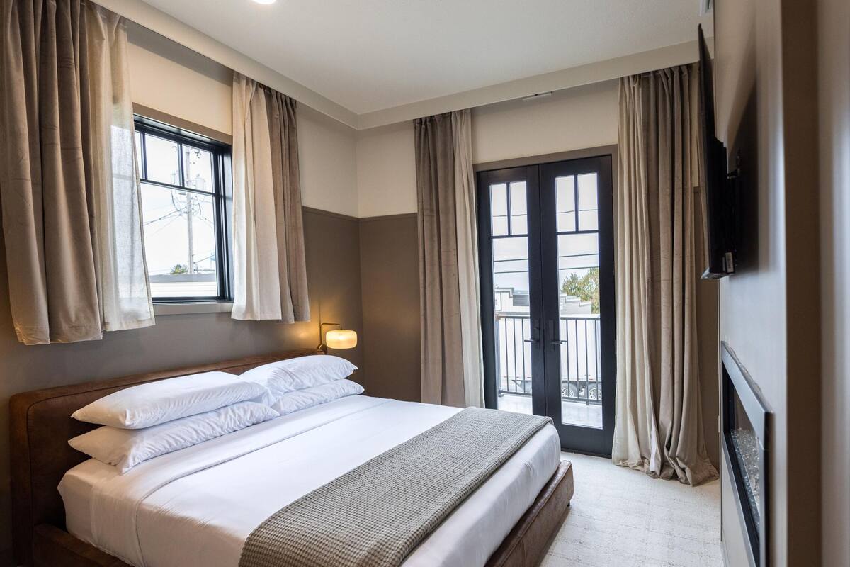 A hotel room with a large bed, a bedside lamp, a TV mounted on the wall, and a balcony door.