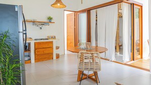 A modern kitchen with a refrigerator, stove, and wooden cabinets. There is a dining table with chairs and a hanging light fixture. - Casa Perezoso-Private pool- 800m from the beach. (Bahia Ballena)