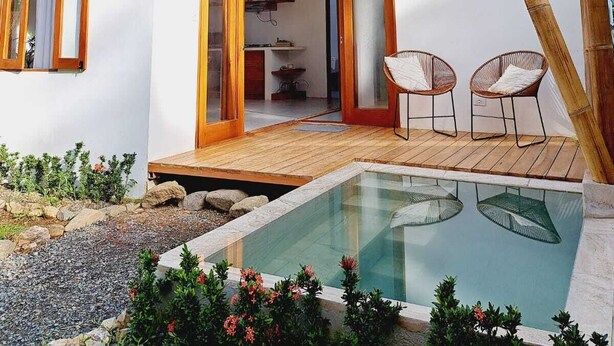 A modern house with a glass door leading to a dining area, a pool, and a wooden deck. - Casa Perezoso-Private pool- 800m from the beach. (Bahia Ballena)