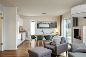 Eine moderne Küche mit weißen Schränken, einem Holztisch und smaragdgrünen Stühlen.