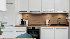 A modern kitchen with white cabinets, a wooden countertop, a built-in oven, and a sink. - Ferienhaus Sonnenweg 32 - Sauna, Garten und Seeblick Inklusive (Diemelsee)