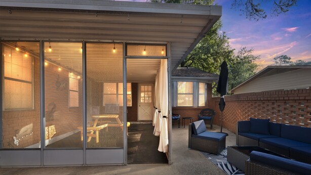 A modern house with a covered patio, a dining area, and a seating area with outdoor furniture. - Forest Retreat - BBQ - Game Room (Shreveport)