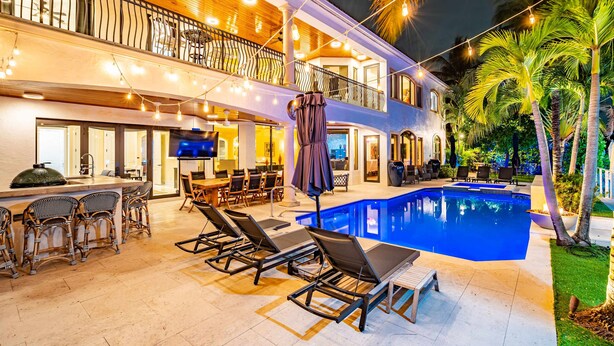 A poolside area with lounge chairs, a bar, and a dining area.