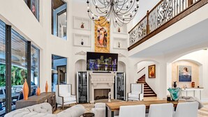 A spacious living room with a fireplace, a dining area, and a staircase leading to an upper floor.
