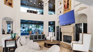 A spacious living area with a fireplace, a large TV screen, and a view of the outside.