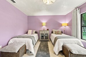 A bedroom with two single beds, a nightstand, a lamp, and a window with curtains. - Lakefront Privacy, Inviting Home on Unique Country Property (DeLand)