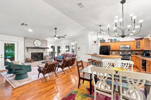 A spacious living area with a fireplace, a dining table with chairs, and a kitchen with wooden cabinets and modern appliances. - Lakefront Privacy, Inviting Home on Unique Country Property (DeLand)