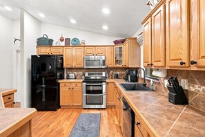 A modern kitchen with wooden cabinets, stainless steel appliances, and a tiled backsplash. - Lakefront Privacy, Inviting Home on Unique Country Property (DeLand)