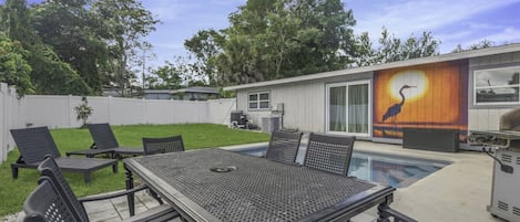 Un patio trasero con piscina, una mesa de comedor y sillas de descanso.