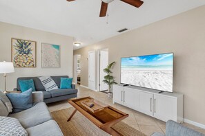 Una sala de estar con sofá, mesa de centro, televisor y una obra de arte en la pared.