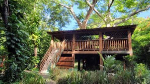 A wooden treehouse with a staircase, surrounded by lush greenery. - San Juan Charm • ForestEdge Retreat • Gated Privacy Near Beach, Airport & Old SJ (San Juan)