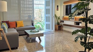 A modern living room with a sofa, coffee table, and a large potted plant. - San Juan Charm • ForestEdge Retreat • Gated Privacy Near Beach, Airport & Old SJ (San Juan)
