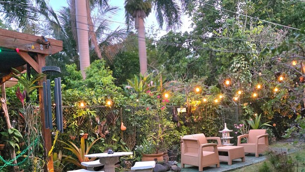 A garden patio with outdoor furniture, a stone table, and string lights. - San Juan Charm • ForestEdge Retreat • Gated Privacy Near Beach, Airport & Old SJ (San Juan)