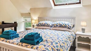 Ein Schlafzimmer mit einem Bett, zwei Nachttischen, einem Fenster und einem Dachfenster.