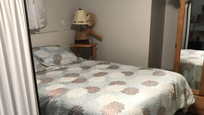 A bedroom with a bed, a nightstand, a lamp, a clock, and a mirror. - Lake front bachelor 
Close to all amenities casino Rama 
Ski hills  (Orillia)