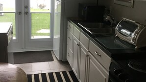 A kitchen with white cabinets, a black stove, a microwave, and a toaster. There is a black and white striped rug on the floor. - Lake front bachelor 
Close to all amenities casino Rama 
Ski hills  (Orillia)