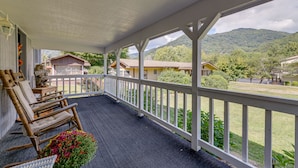A covered porch with a view of a mountain, a wooden rocking chair, and a flower pot. - 5 Mi to Cataloochee Ski Area! Family Home w/ Views (Maggie Valley)