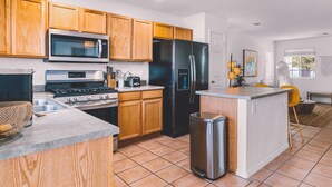 A modern kitchen with wooden cabinets, stainless steel appliances, and a tiled floor.