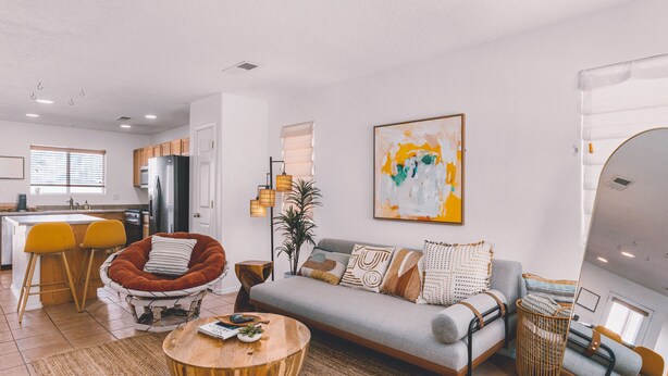 A modern living room with a sofa, coffee table, and a dining area with chairs.