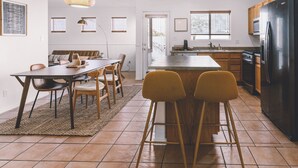 A modern kitchen with a central island, wooden cabinets, and a black refrigerator.