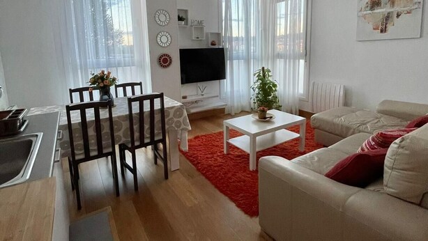 Un salon moderne comprenant un coin repas, un téléviseur à écran plat et un tapis rouge.