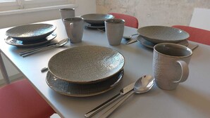 Une table à manger dressée avec des assiettes, des bols, des tasses et des couverts.