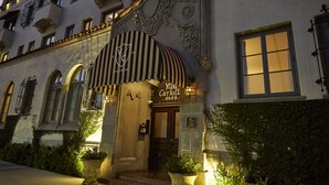A hotel entrance with a classic design, featuring a large arched entrance, a sign with the name 'Villa Carroll', and a well-lit facade.