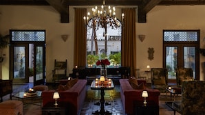A cozy lounge with a large chandelier, plush seating, and a view through a window.