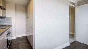 A modern kitchen with white cabinetry and a dark wood floor. - Bakersfield (London)