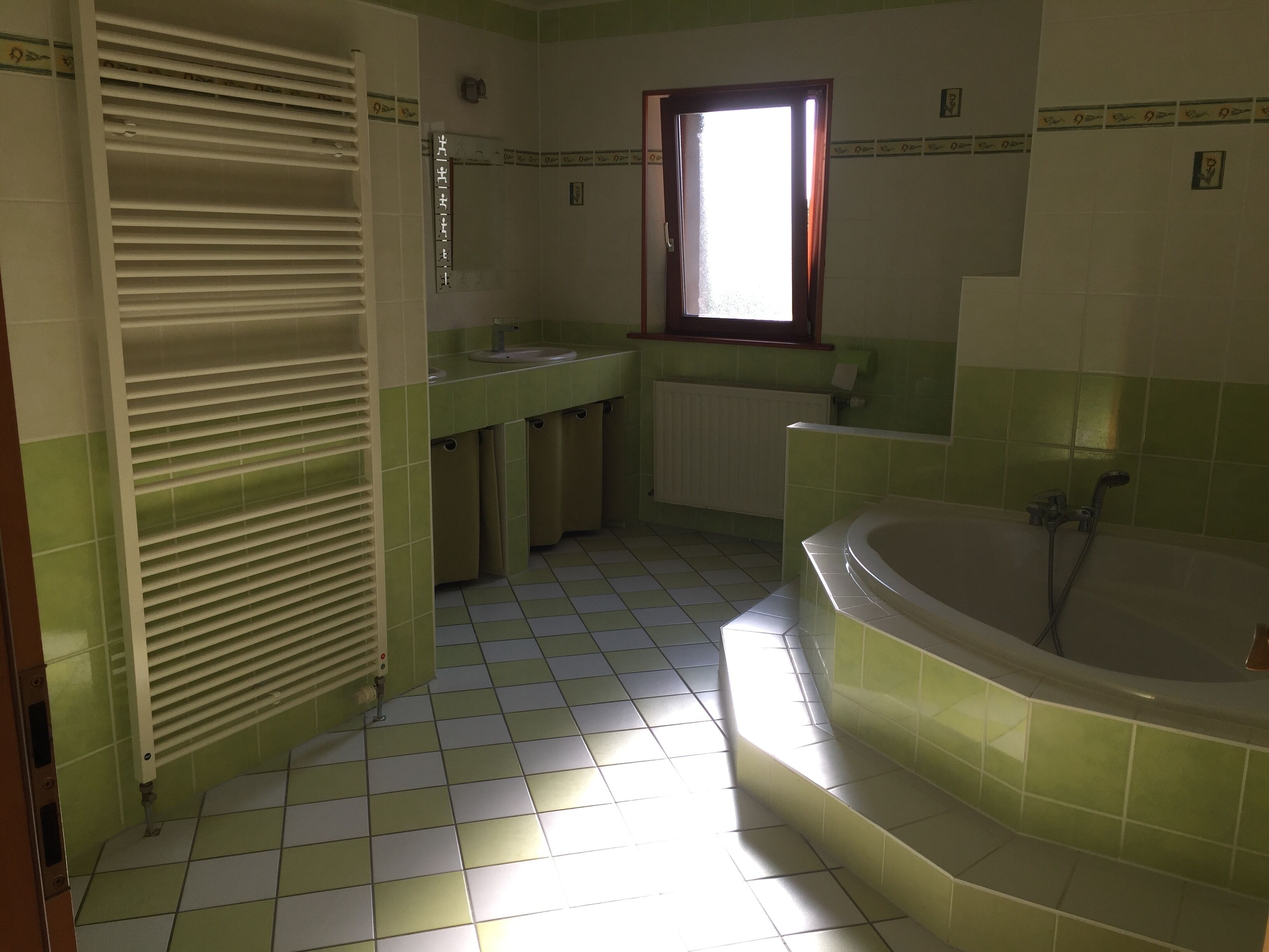 Une salle de bain avec une baignoire, un lavabo et une fenêtre.