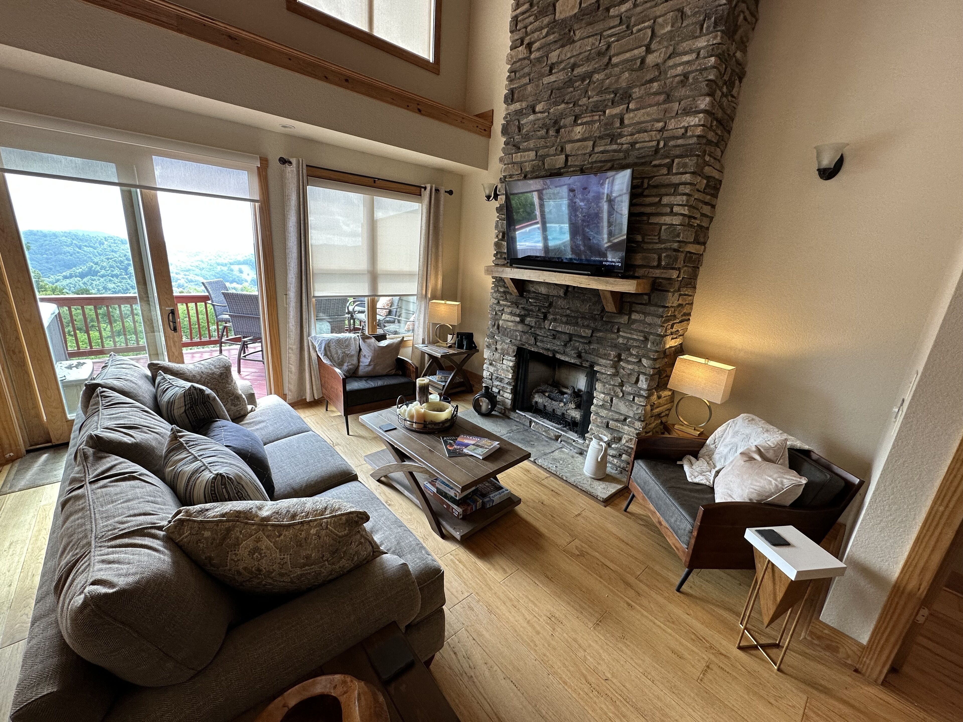 Una sala de estar acogedora con chimenea de piedra, un sofá confortable y un televisor montado en la pared.