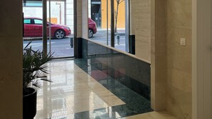 Een hotel lobby met een marmeren vloer, glazen deuren en uitzicht op de straat.