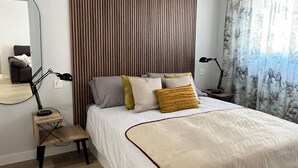 Ein modernes Schlafzimmer mit einem großen Bett, zwei Nachttischen, einem Spiegel und einer Deckenleuchte.