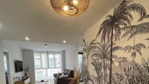 Ein modernes Wohnzimmer mit einer großen Wandmalerei, einem runden gewobenen Couchtisch und einem gelben Sessel.