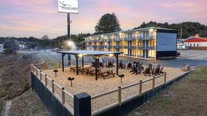 A motel with a covered outdoor seating area, picnic tables, and a signboard. - The Mallard Hotel (Copperhill)