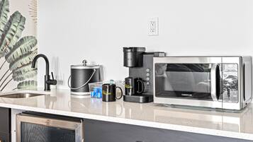 Una cocina moderna con un refrigerador de acero inoxidable, una cafetera, un microondas y un lavabo.