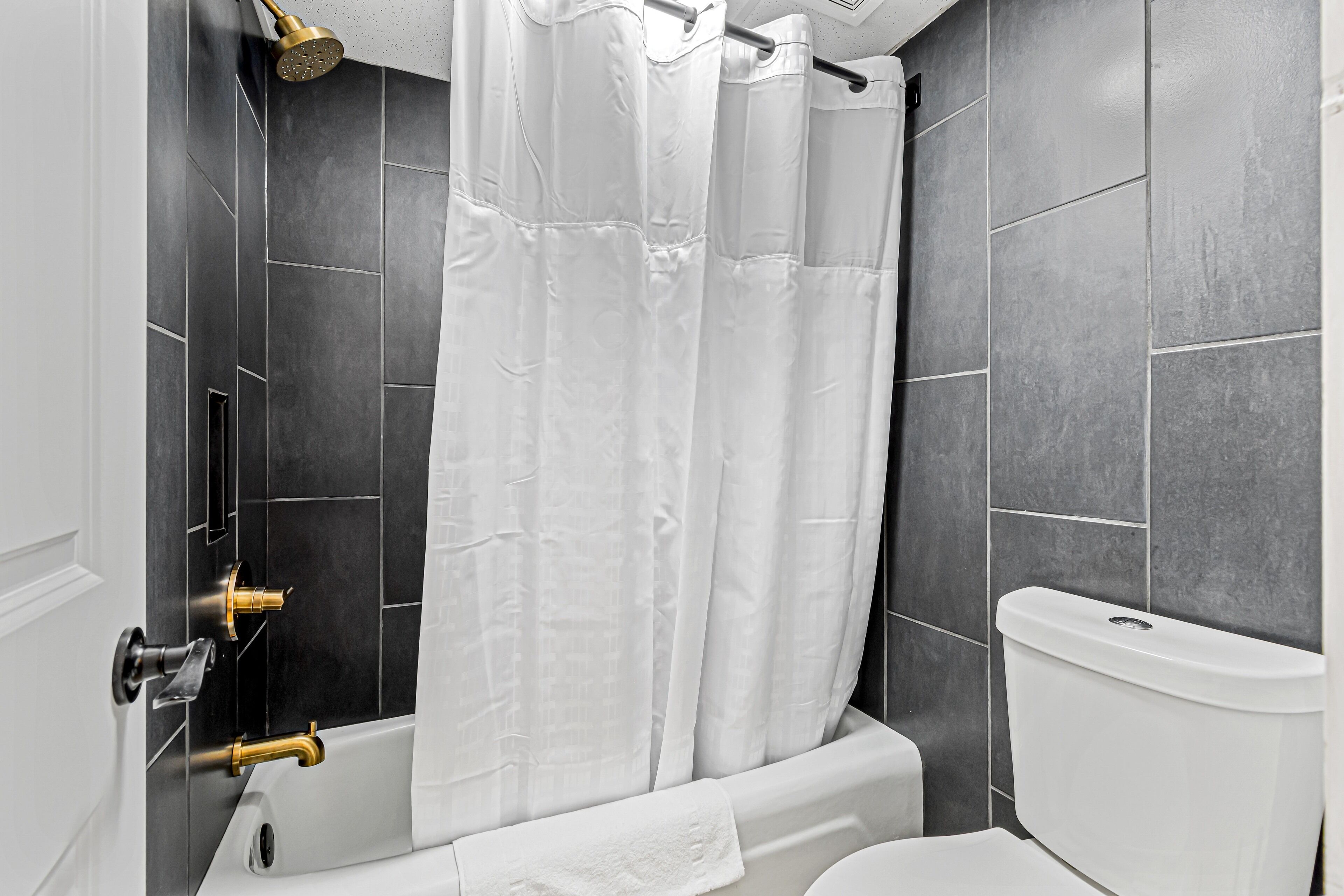 A bathroom with a bathtub, a toilet, and a shower curtain.