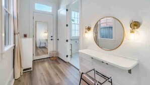 Un couloir avec un mur blanc, un miroir rond et une étagère blanche.