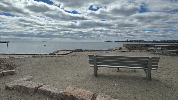 A bench on a sandy beach with a view of the water and clouds in the sky. - Sunset Studio (Branford)