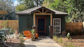 A small wooden structure with a door and windows, surrounded by a wooden fence and vegetation. - Modern Farm House Pensacola, Fl
Centrally located in the heart of Pensacola  (Pensacola)