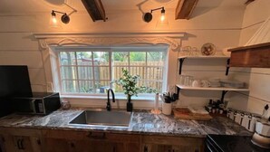 A kitchen with a granite countertop, a sink, a window with a view of a backyard, and wooden cabinets. - Modern Farm House Pensacola, Fl
Centrally located in the heart of Pensacola  (Pensacola)