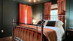 A bedroom with a metal bed frame, a chandelier, and red curtains. - Modern Farm House Pensacola, Fl
Centrally located in the heart of Pensacola  (Pensacola)