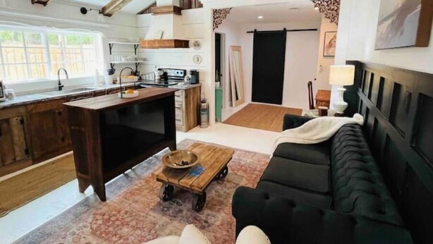 A spacious living area with a dark sofa, a wooden coffee table, and a kitchen with a large island. - Modern Farm House Pensacola, Fl
Centrally located in the heart of Pensacola  (Pensacola)