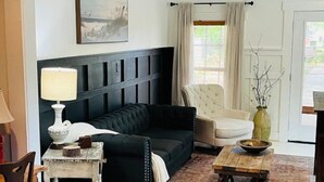 A living room with a dark-colored sofa, a white armchair, a wooden coffee table, and a lamp. - Modern Farm House Pensacola, Fl
Centrally located in the heart of Pensacola  (Pensacola)