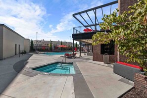 A pool area with a rectangular pool, lounge chairs, and a covered seating area.