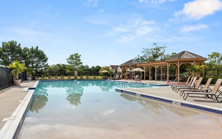 A swimming pool with lounge chairs and a gazebo.