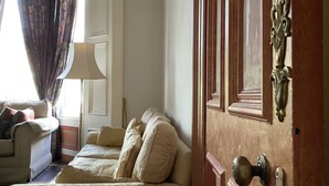 Ein Zimmer mit einer Sofagarnitur, einer Lampe und einer Tür mit einer verzierten Griff.