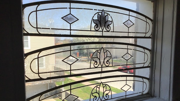 A window with decorative metal grilles and a view of a residential street.