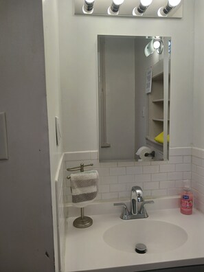 Un baño con un lavabo blanco, un espejo y un toallero.