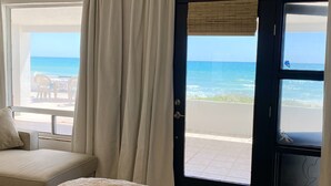 A room with a bed, a sofa, and a view of the ocean through a door. - Beach Front Home in beautiful Playa Encanto gated community 3bed/3bath (Playa Encanto)